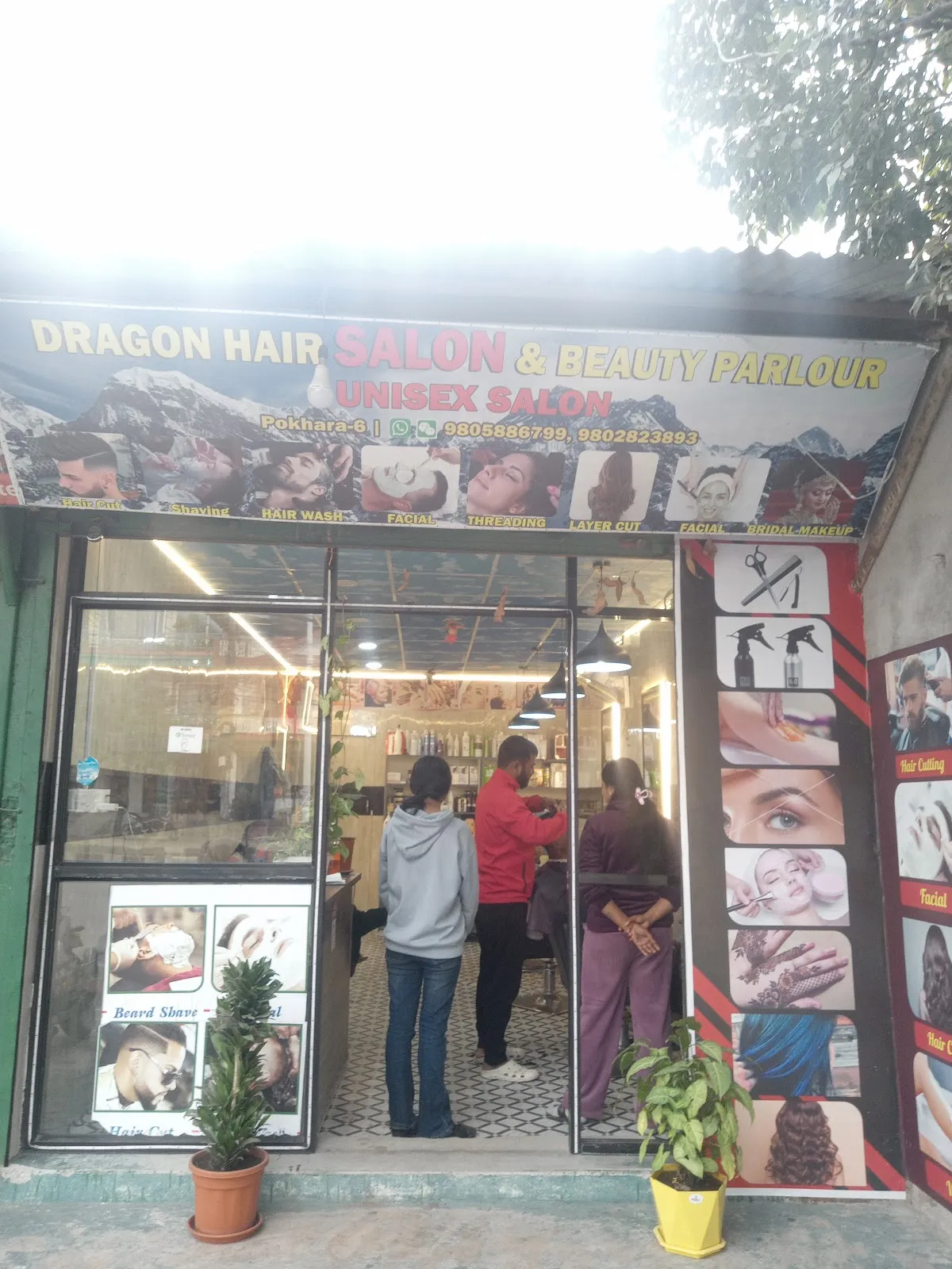 The Dragon Hair Salon storefront in daylight with mountain mural sign